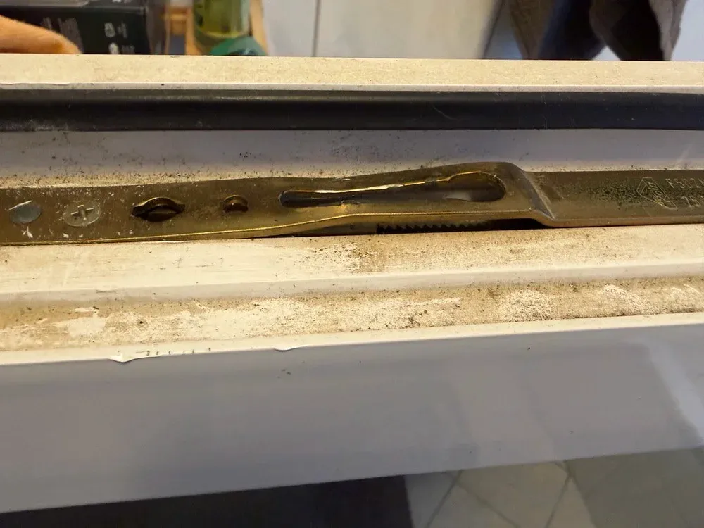 Beschlagschiene im Flügelfalz eines Fensters, verschmutzt und trocken gelaufen